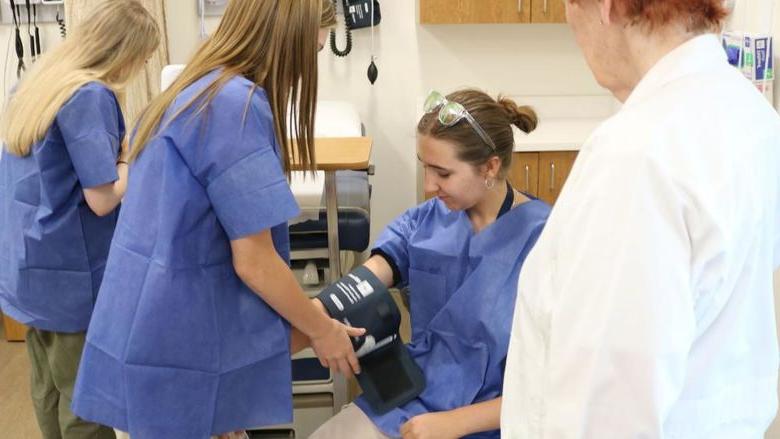 MedCamp 2024 participants checking vitals while Nursing professor observes.